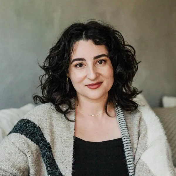 My headshot: A white woman with some grey in her wavy brown hair smiles gently.