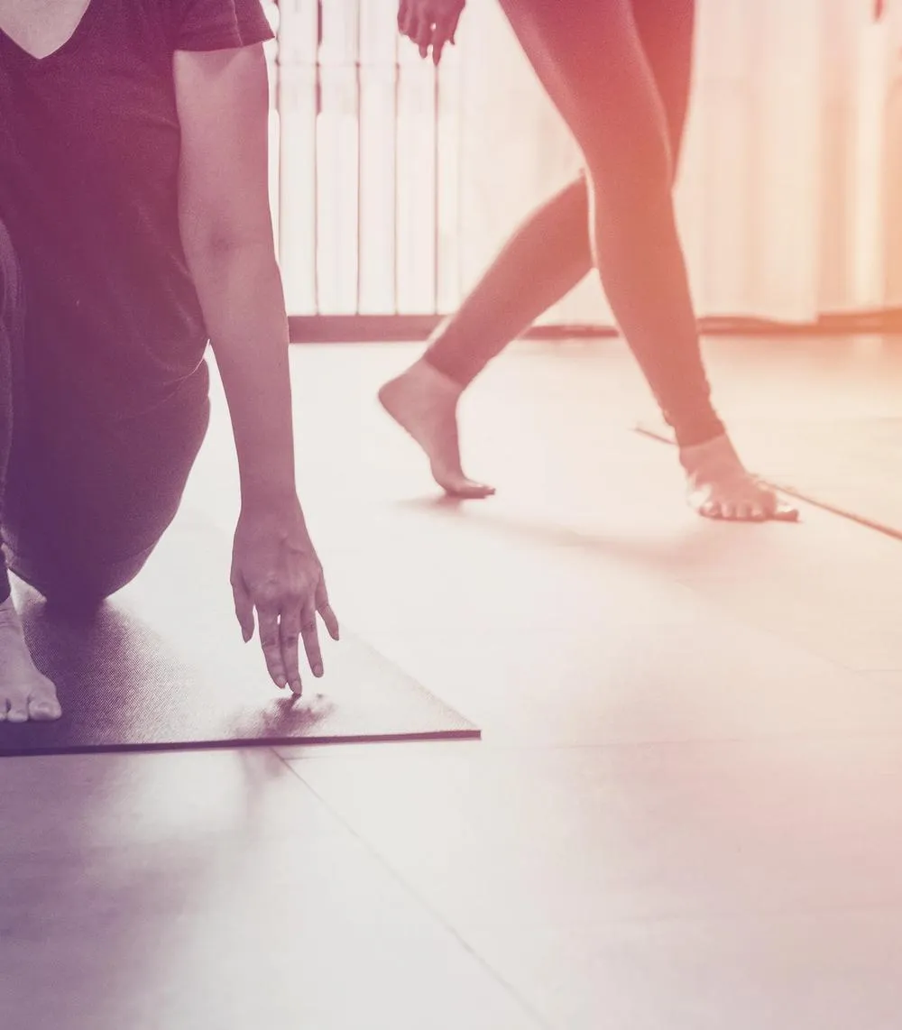 Hands and feet of three people doing various stretches on yoga mats.