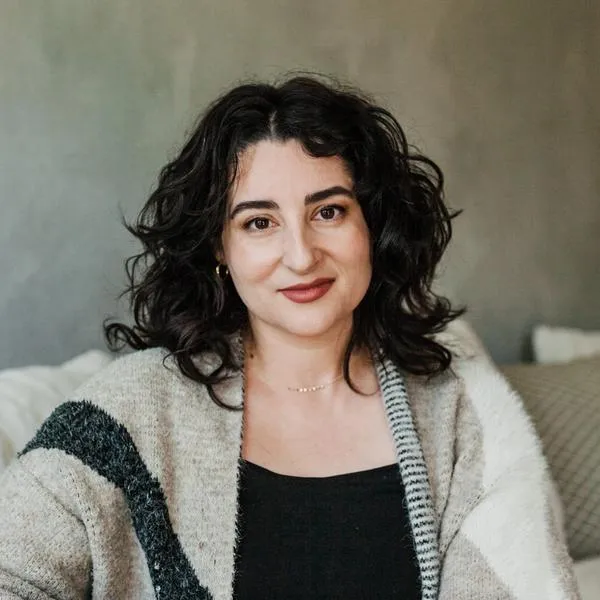My headshot: A white woman with some grey in her wavy brown hair smiles gently.